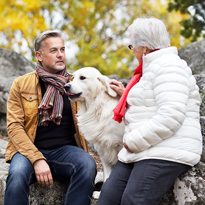 pensionärer och hund på klippa i skogen