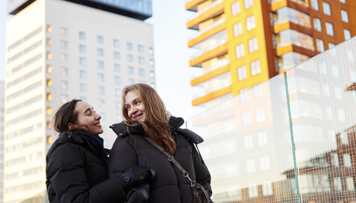 Två kvinnor framför höga hus.