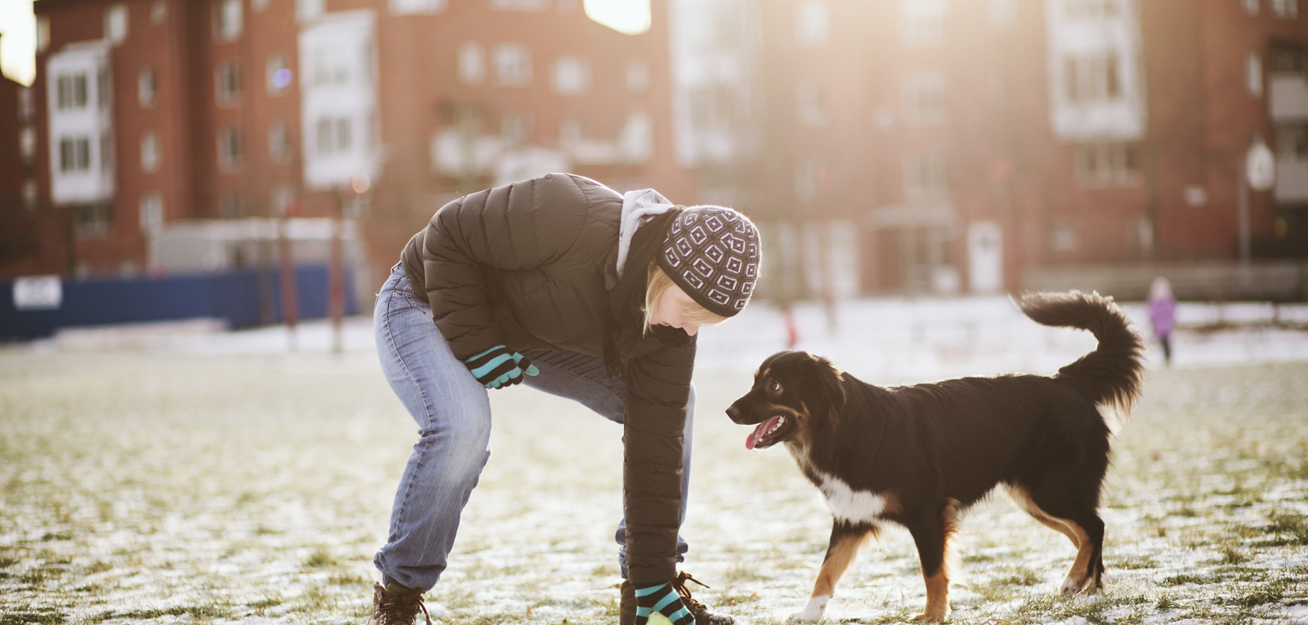 En man och en hund utomhus, i bakgrunden hus.