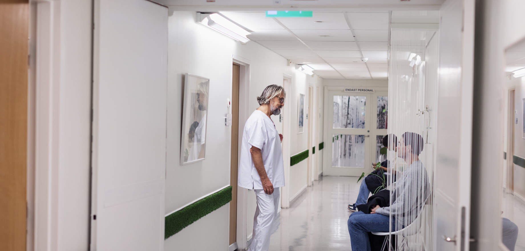 En personal talar med två i en sjukhuskorridor