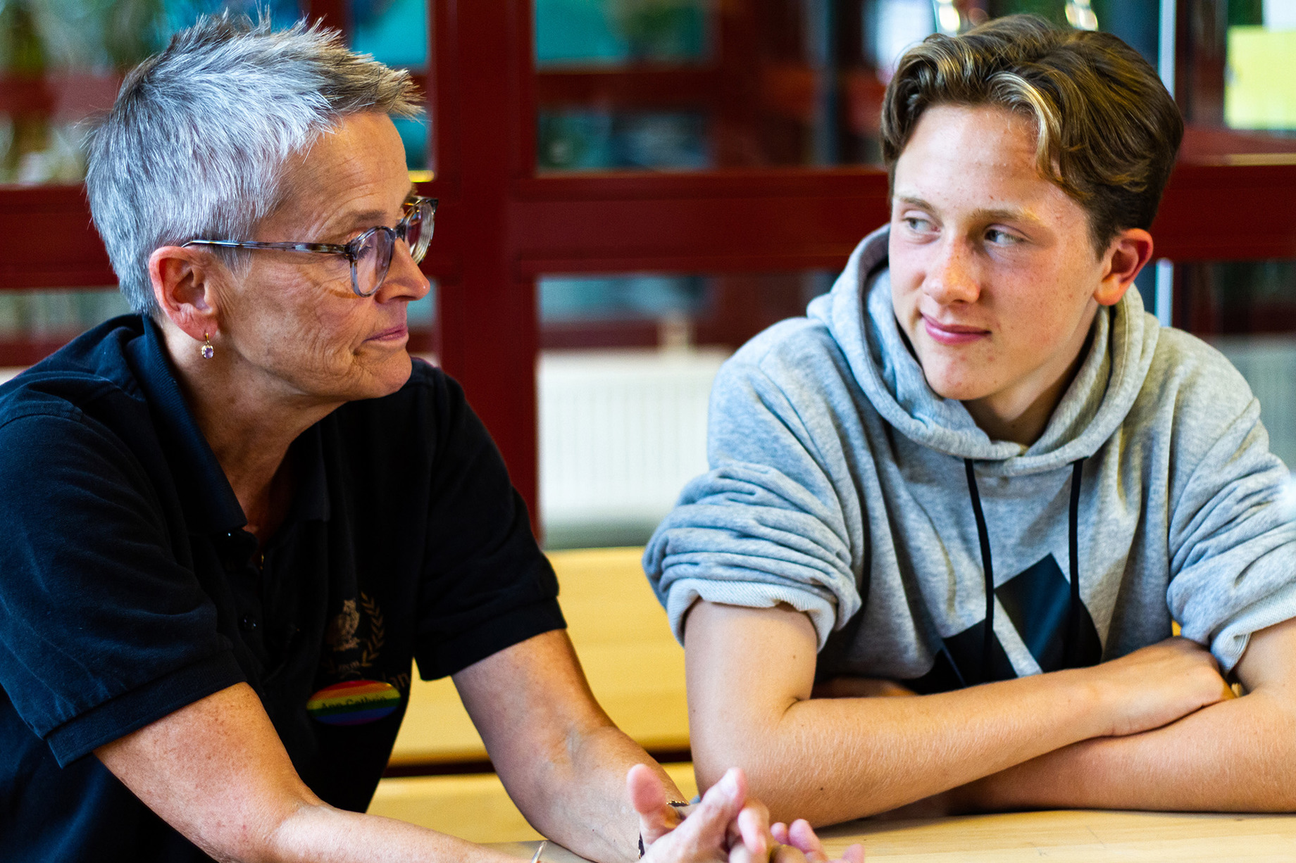 en äldre man och en yngling sitter vi ett bord och pratar