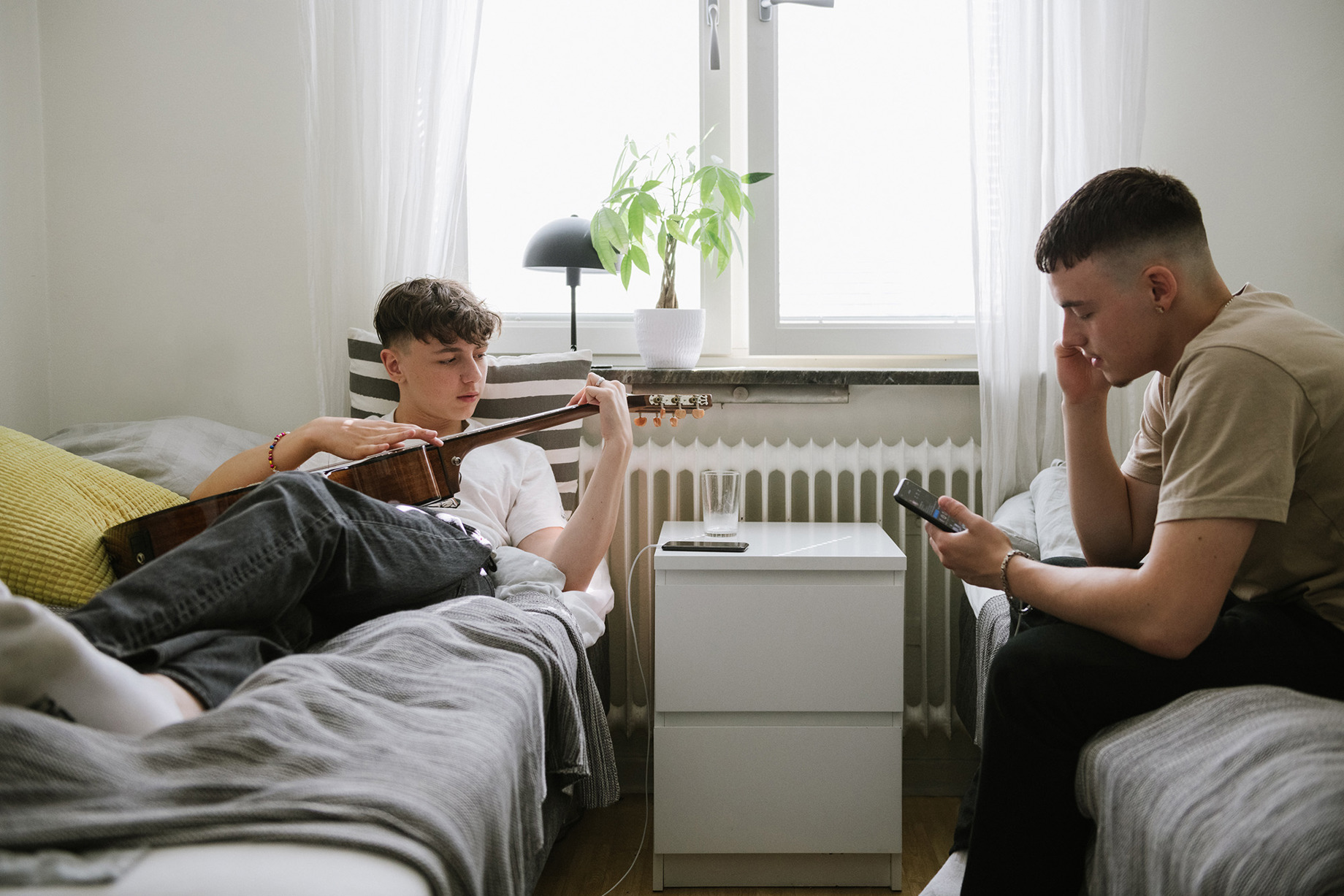 Två unga män som samtalar sittandes i varsin säng