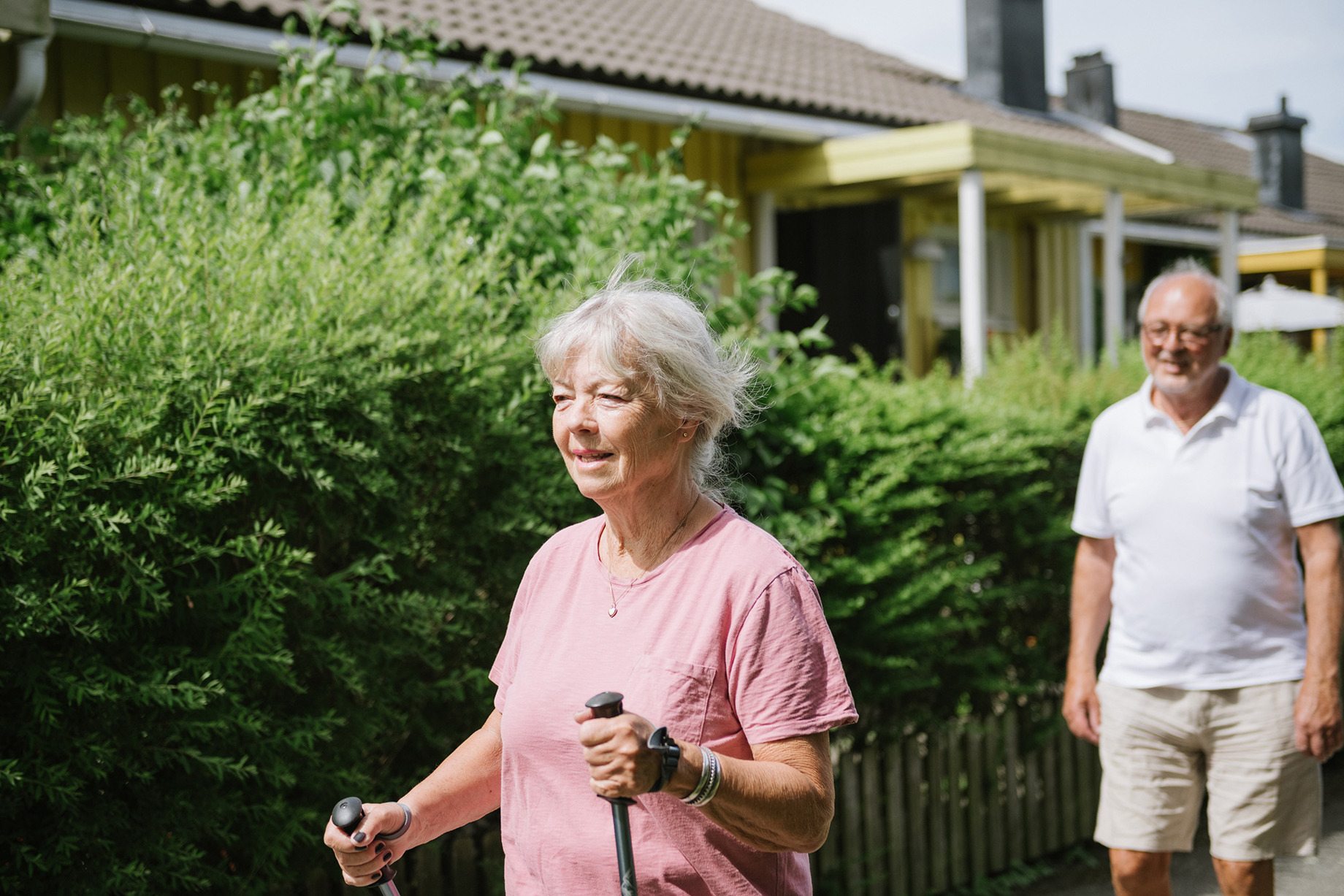 En äldre kvinna med gåstavar och en man, utomhus